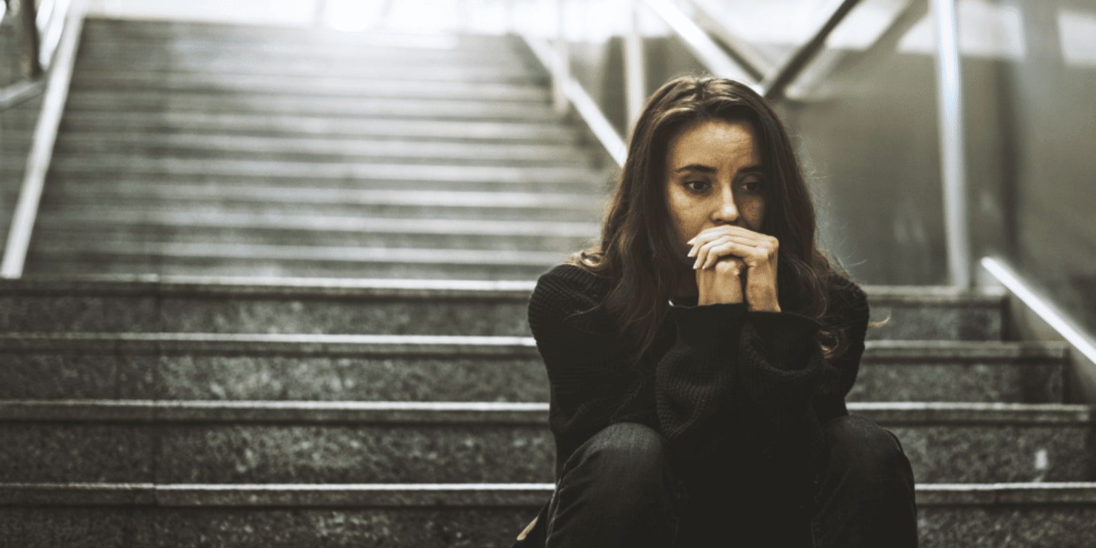 A young woman sitting on a staircase concerned