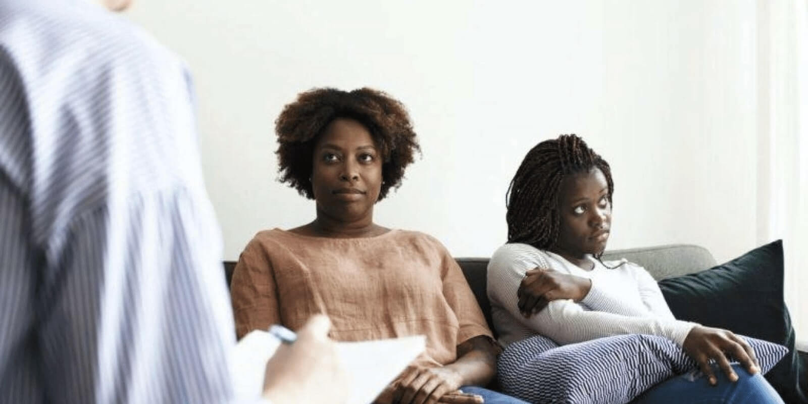 A parent and teen child talking to listening to a therapist