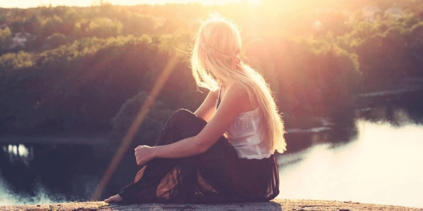 A teen girl looking at sunset across the lake