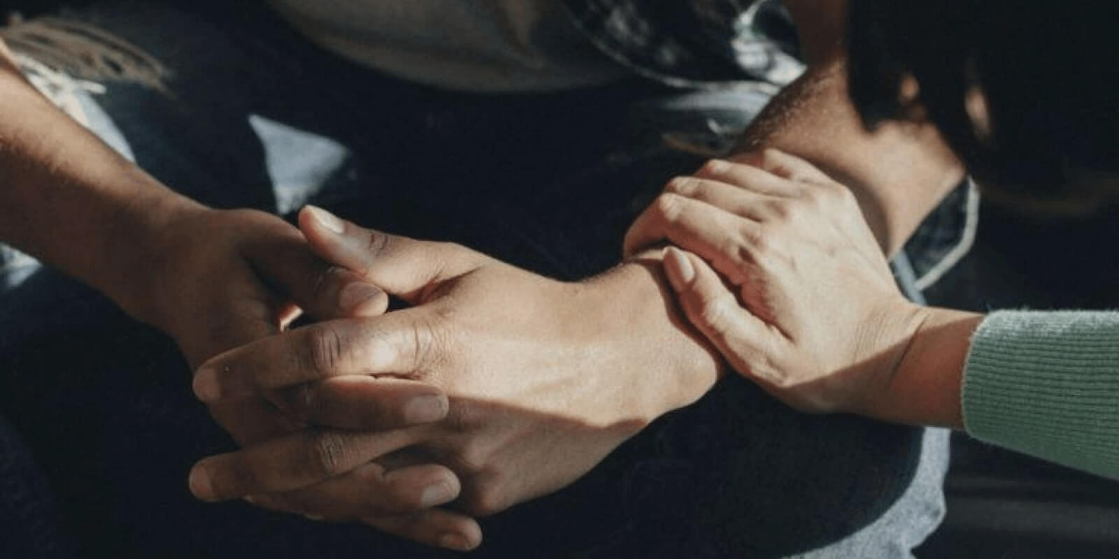 A woman's hand holding the wrist of a troubled teen warmly