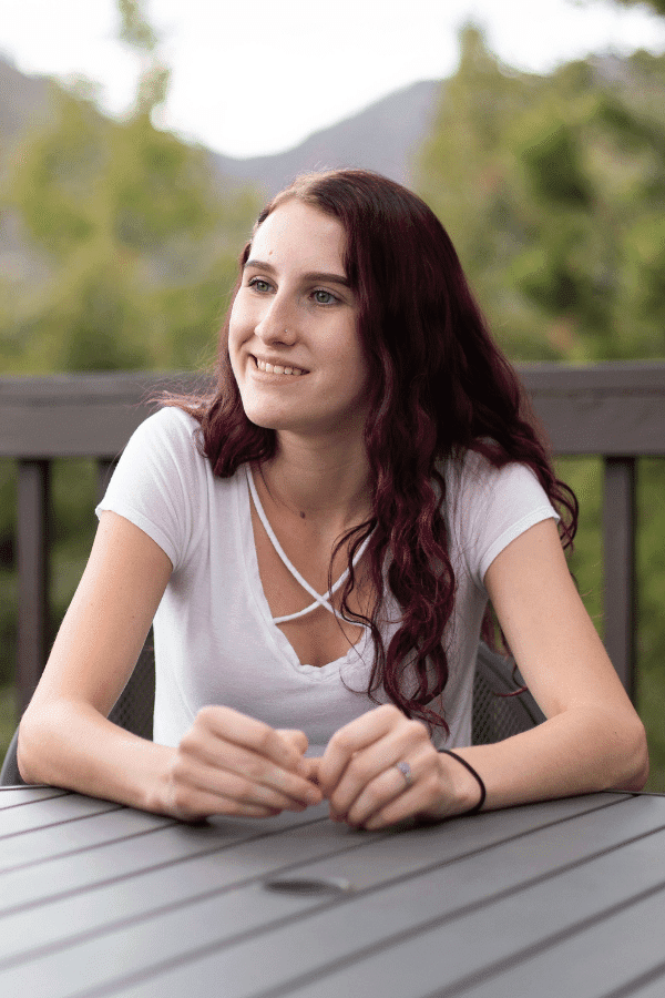 Teen girl smiling at something outside the angle sitting at the table outside in Colorado