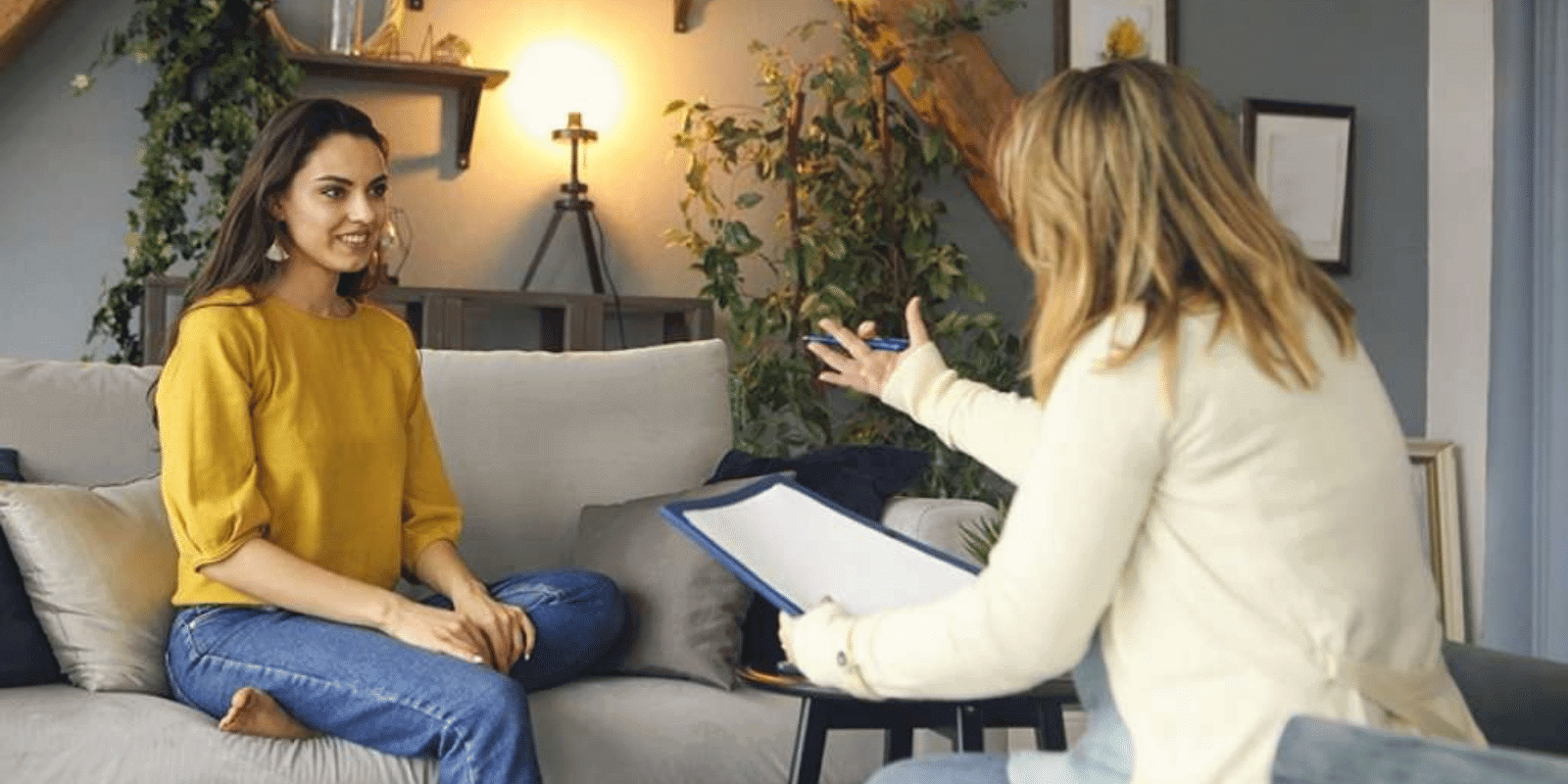 Young adult sitting comfortably in a couch talking to a therapist in front of her