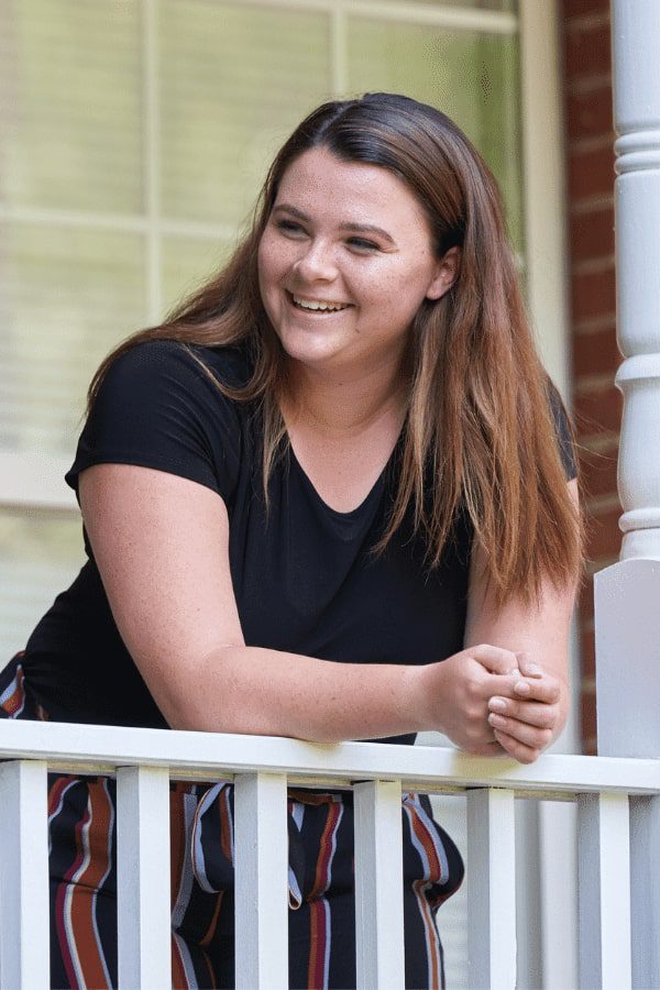 A teen girl smiling at someone while leaning at a terrace fence