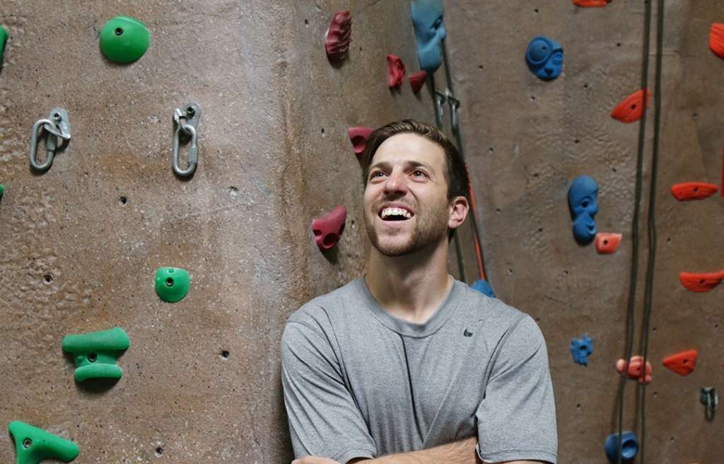 Adult man looking excited in front of rock climbing wall