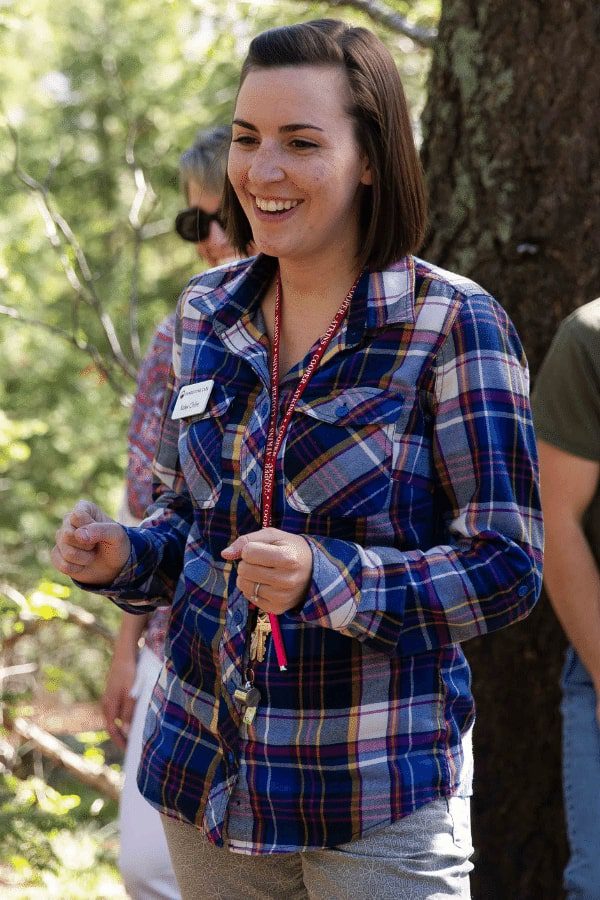 there is a woman that is standing in the woods with a cell phone