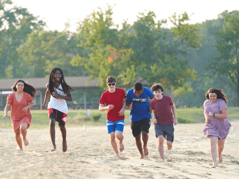 Teens running down the beach