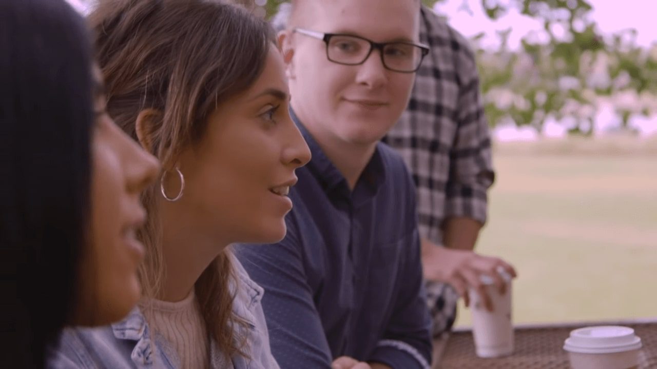 Young adult group smiling outside with drinks.