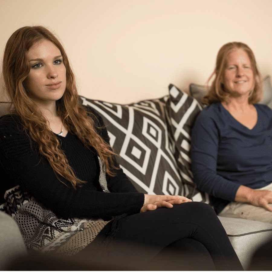A teenage girl with her mom sitting on the couch