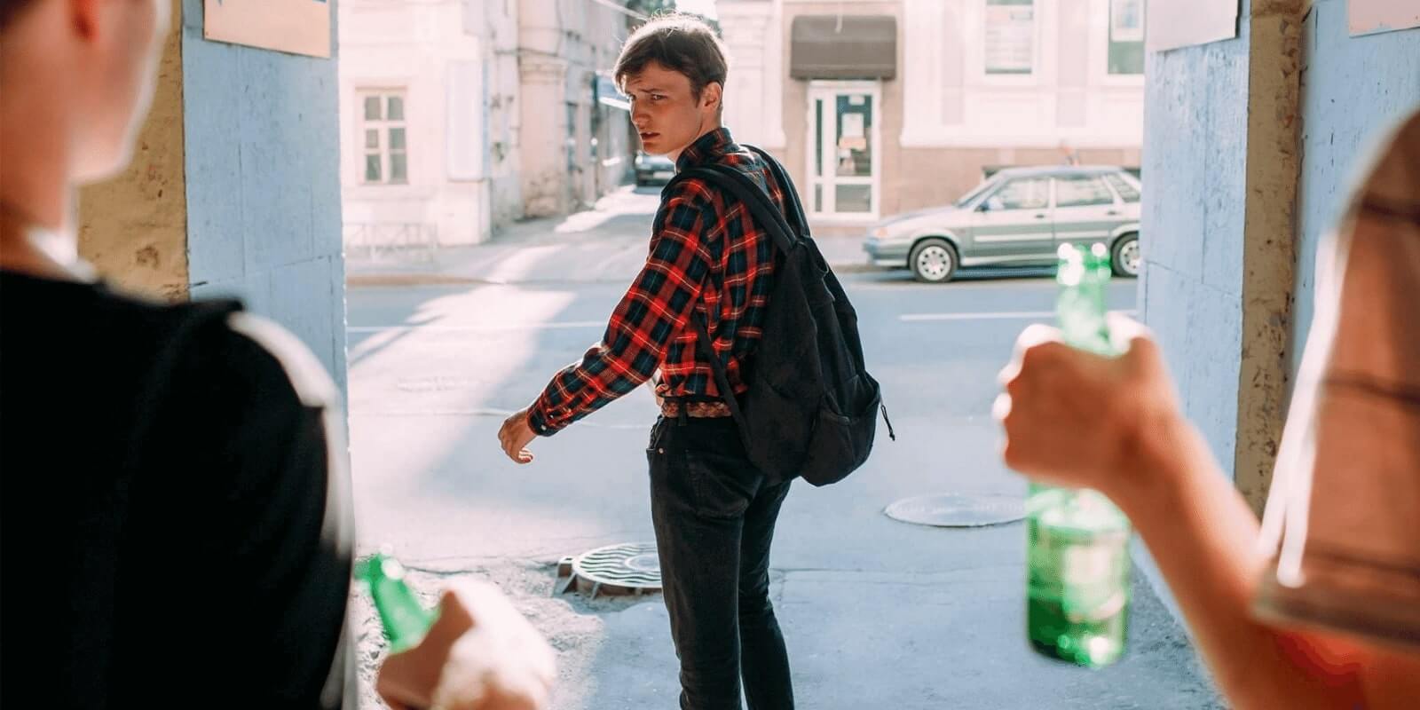 High school teen staying away from peer pressuring friends holding alcohol bottles