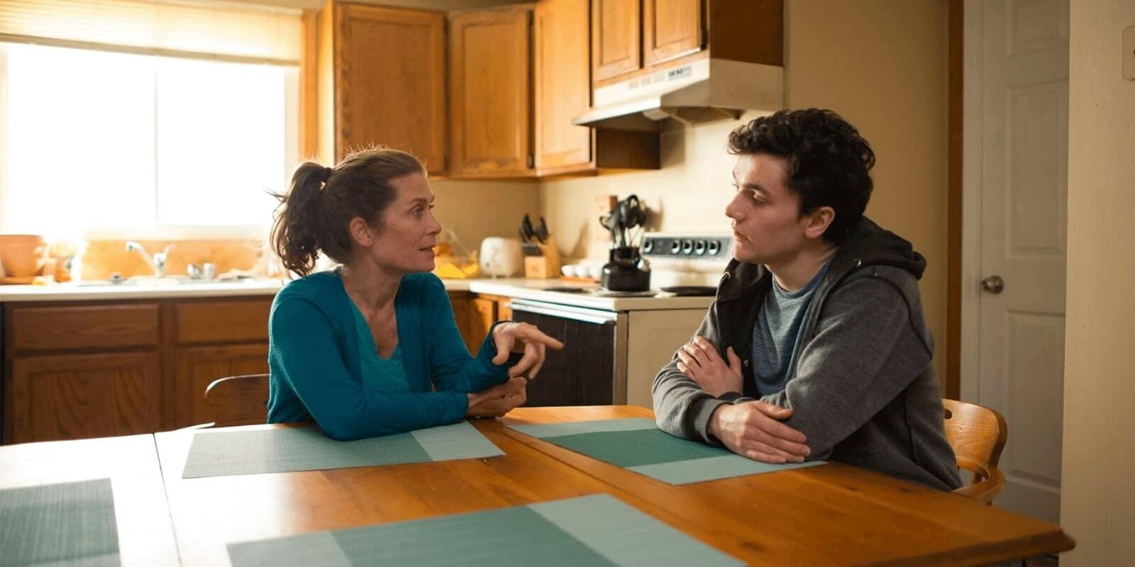 Mom talking to her teenage son at the kitchen table