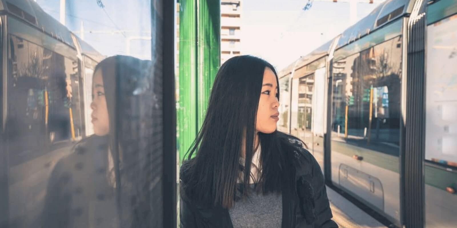 A teen girl staring at the train in the train station