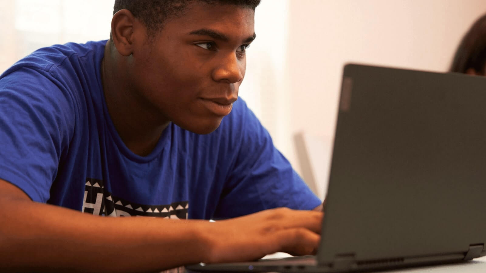 A teenage boy looking at a laptop screen