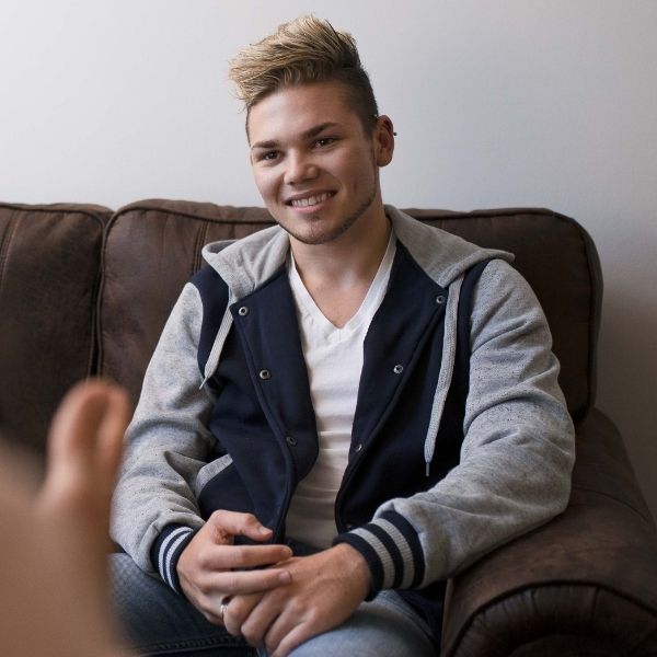 Teenage boy sitting on a leather couch.