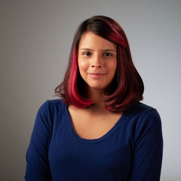 Teenage girl with pink streaks in her hair smiling at the camera.