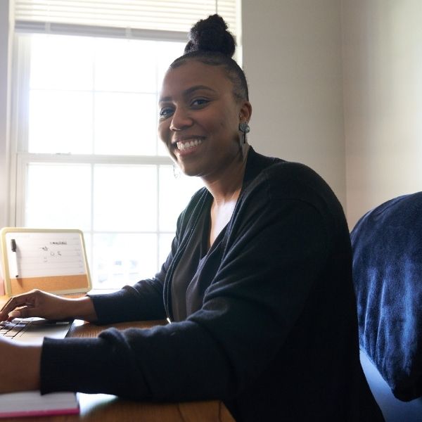 A clinician sitting and smiling at a computer.