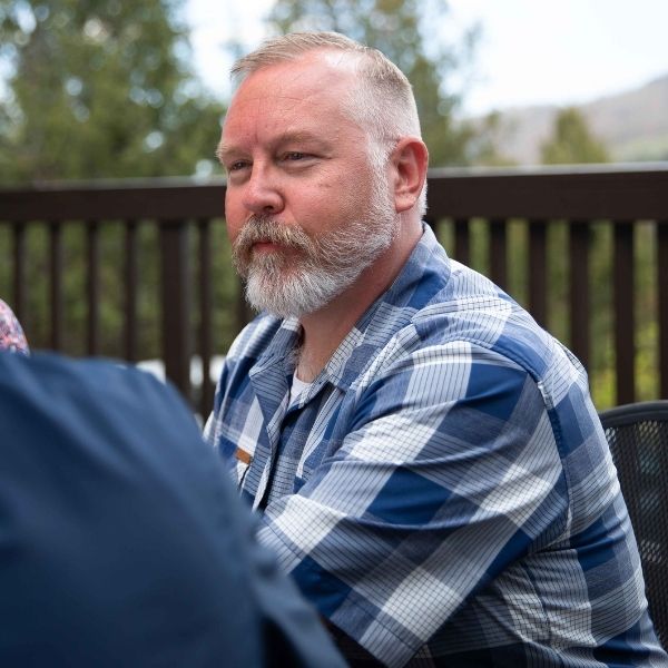 Older man with white hair sitting outside.