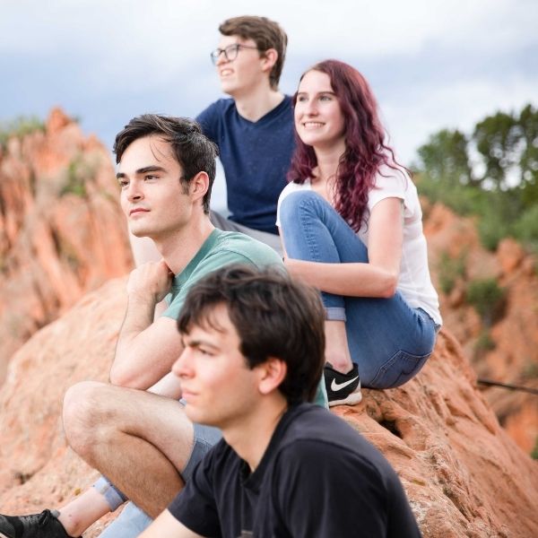 Teenagers sitting on canyon rocks looking out at the horizon.