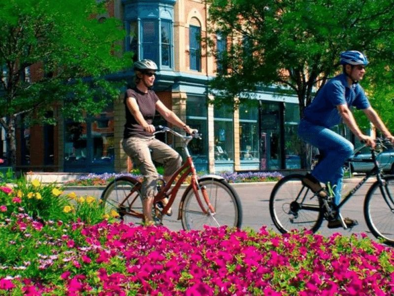 A cute couple riding bicycle next to flower garden in Fort Collins, Colorado