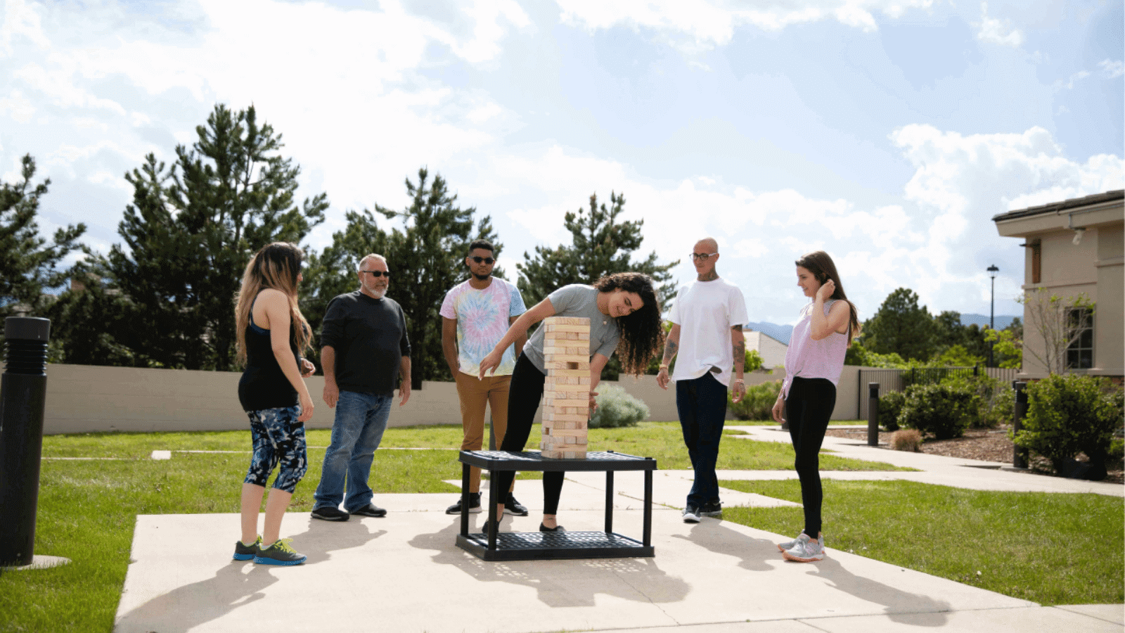 Group of young adult playing wooden Jenga outside rehab
