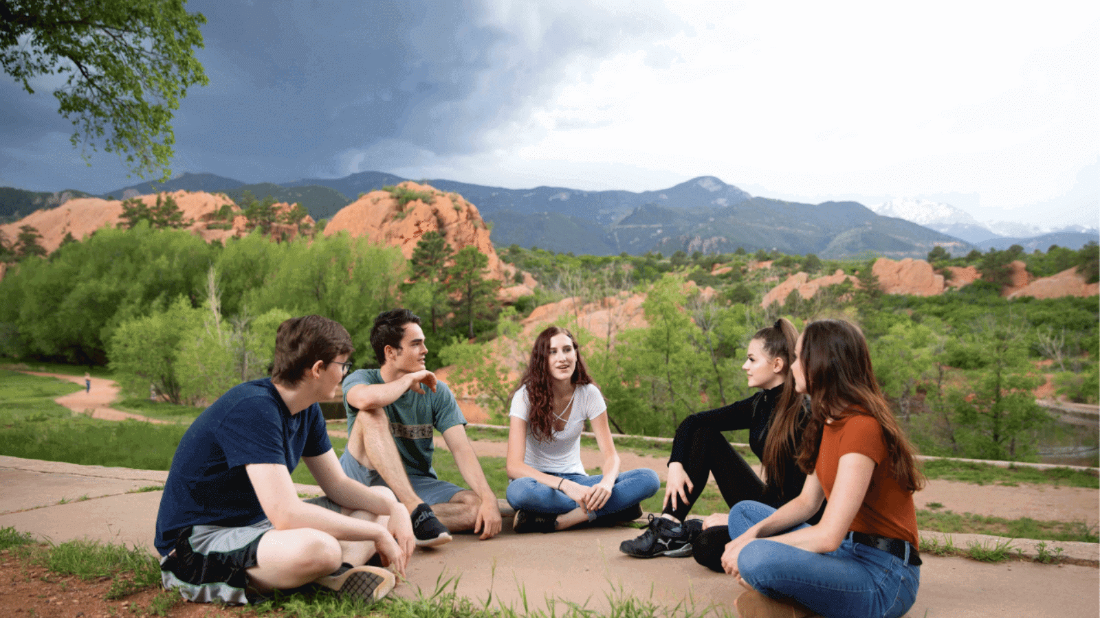 Group of young adults sitting in a circle on top of a Colorado mountain
