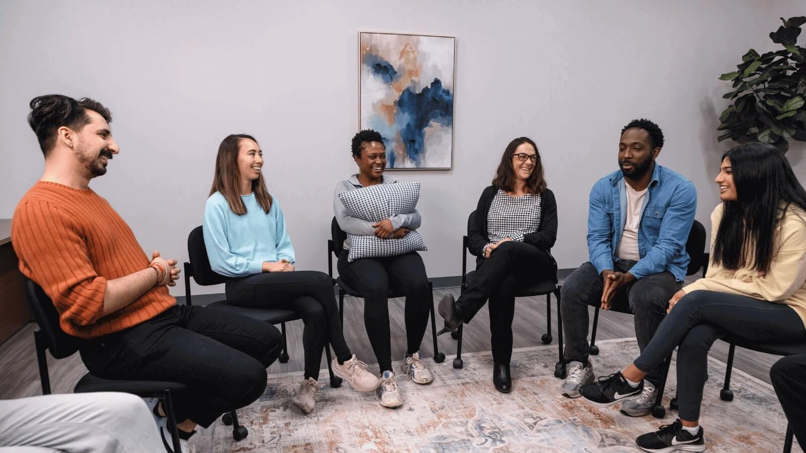 A diverse group of young adults sitting in a circle and laughing.