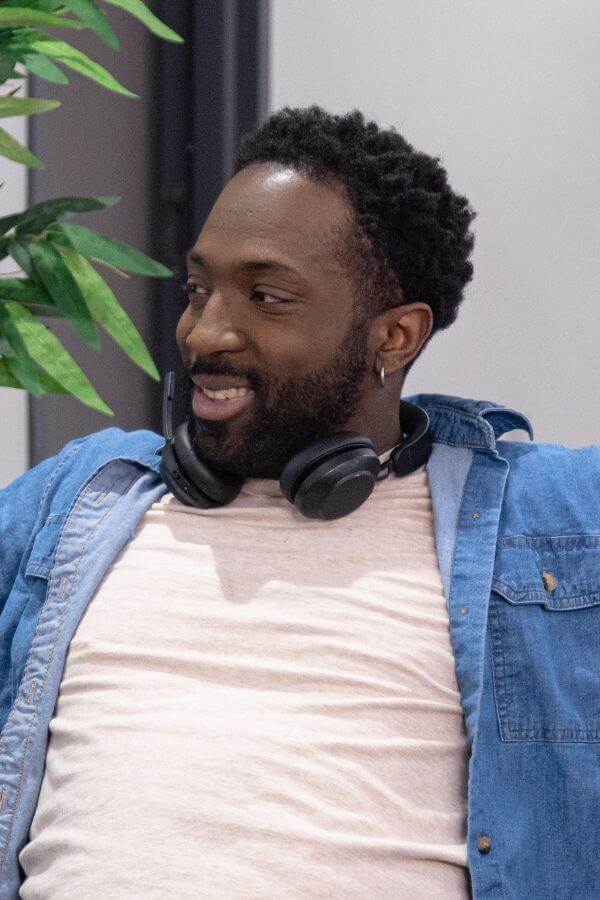 Black man smiling with headphones around his neck.