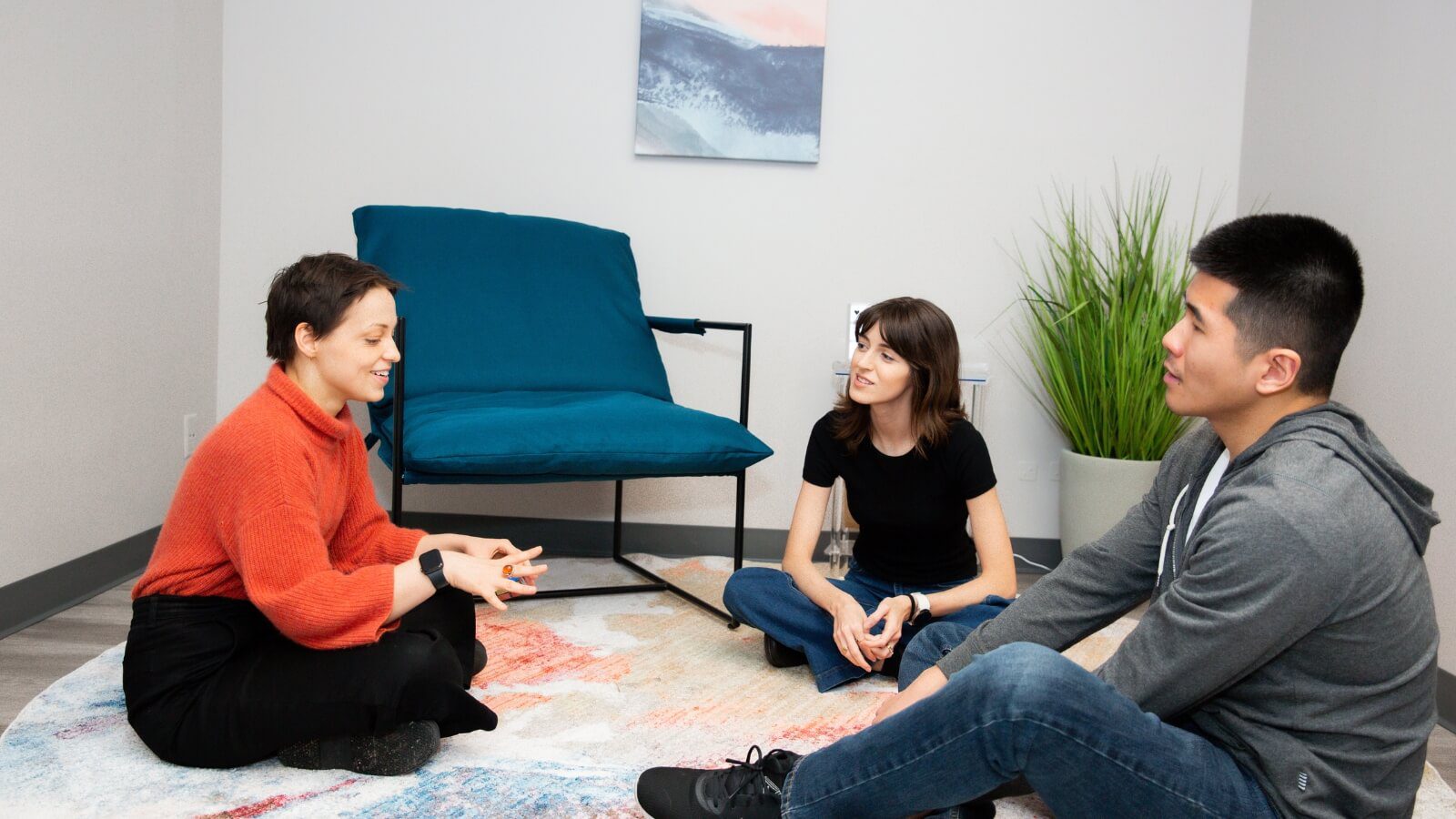 Three people in a group therapy room in an exciting conversation.