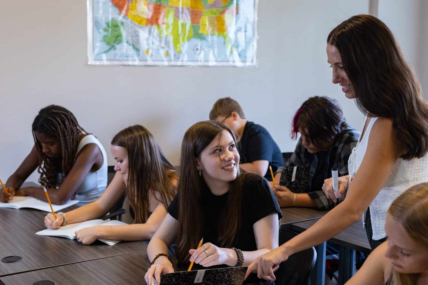 A teen talking to a teacher in a classroom